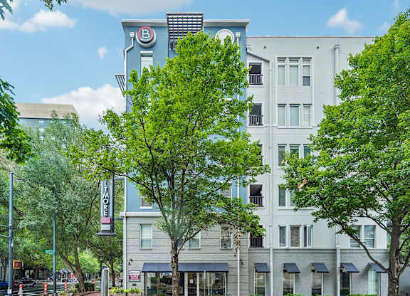 A tree in front of a building with a sign that says