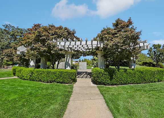 A white arched structure with trees growing on it.