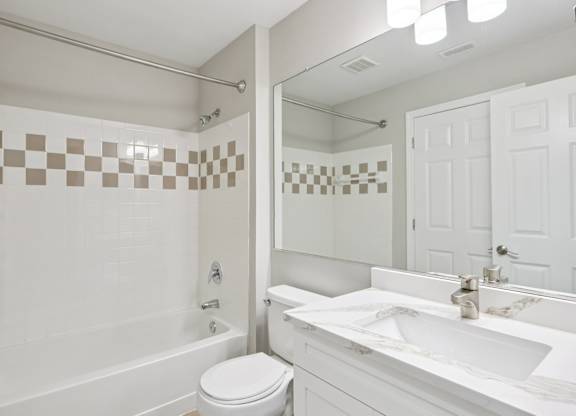 A white bathroom with a checkered tile wall.