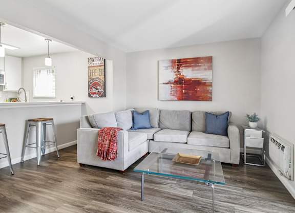 A living room with a white couch and a red and white painting on the wall.