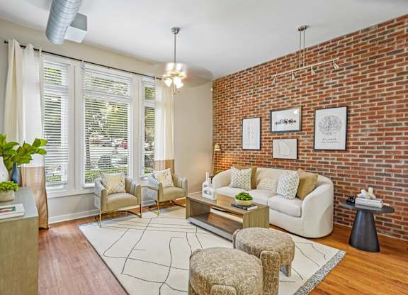 A living room with a white couch, a chair, a table, and a plant.