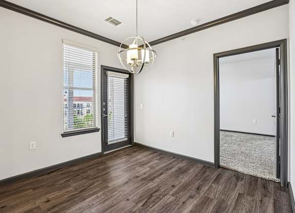 A room with a wooden floor and a chandelier hanging from the ceiling.