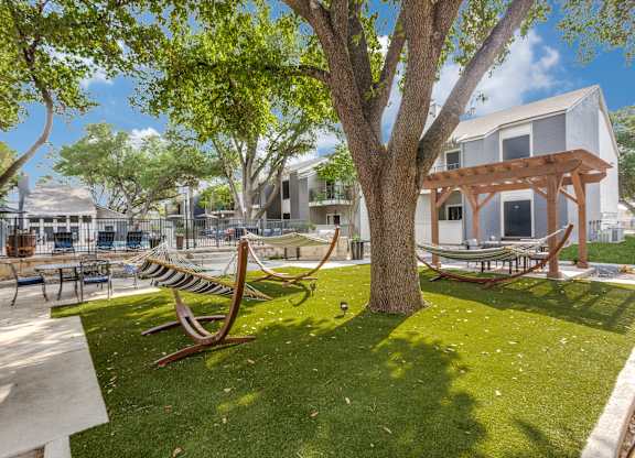 A park with a bench and a tree in front of a building.