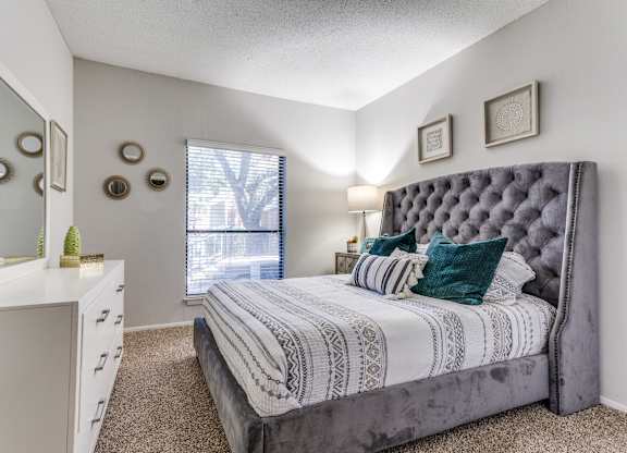 a bedroom with a large bed and a dresser with a mirror
