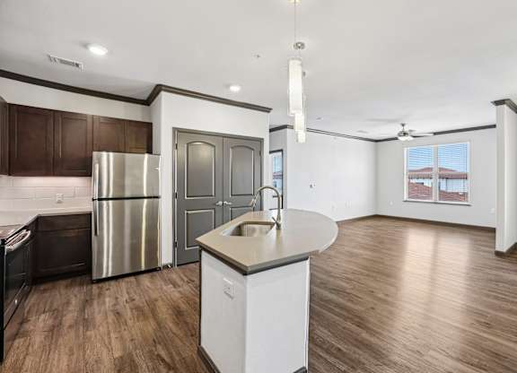 A kitchen with a refrigerator, sink, and cabinets.
