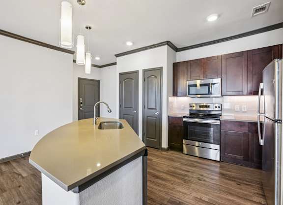 A modern kitchen with a wooden floor and stainless steel appliances.