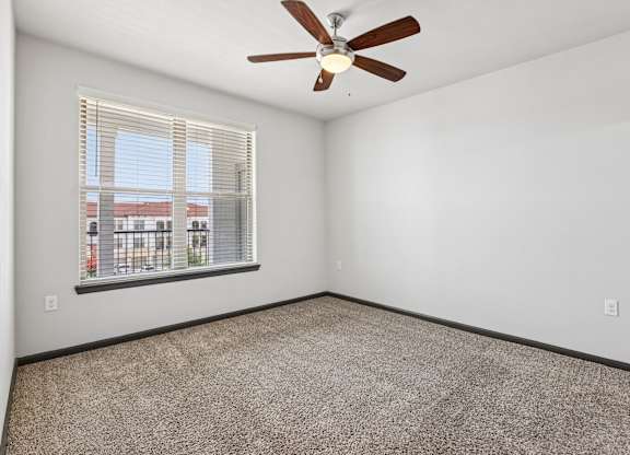 A room with a ceiling fan and a window with blinds.