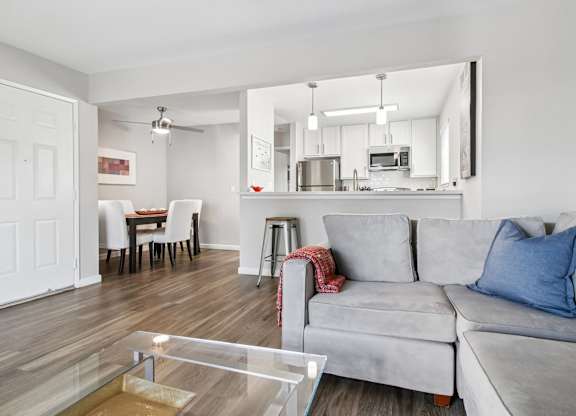 A modern living room with a grey couch and a glass coffee table.