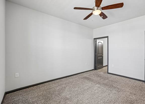 A room with a ceiling fan and carpeted floor.