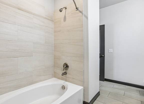 A white bathtub in a bathroom with a shower head above it.