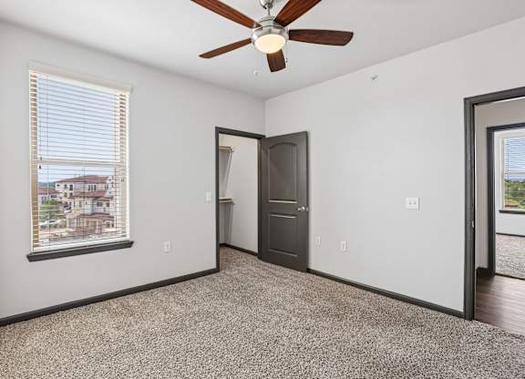 A room with a ceiling fan and a window with blinds.