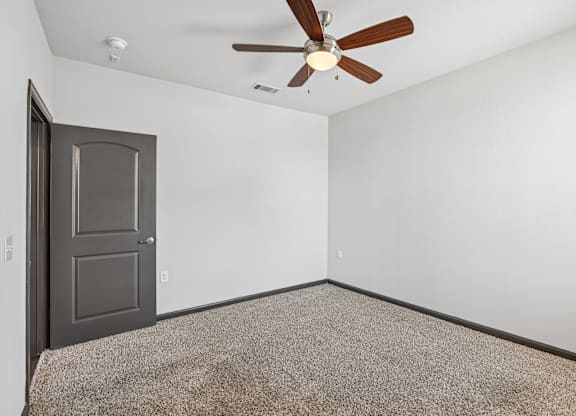 A room with a ceiling fan and a door.