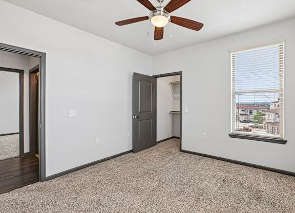 A room with a ceiling fan and a window with blinds.
