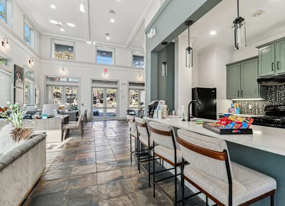 A kitchen with a long counter and chairs.