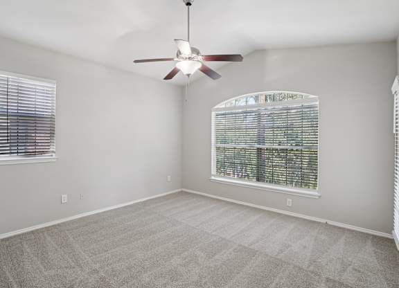A room with a ceiling fan and a window with blinds.
