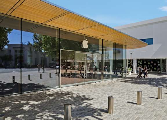 The Apple store has a glass facade and a wooden awning.