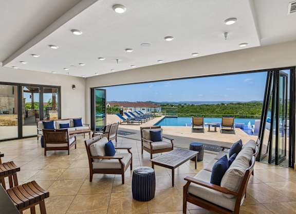 A modern living room with a view of the pool and outdoor furniture.