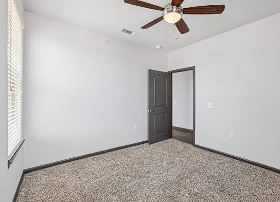A room with a ceiling fan and carpeted floor.