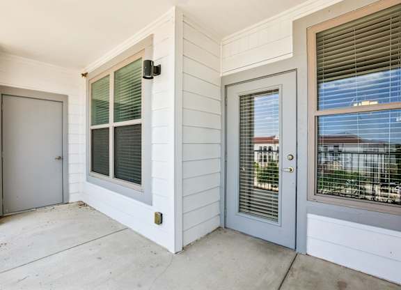 A white house with a grey door and a window with blinds.