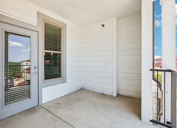 A white house with a grey door and a window with blinds.