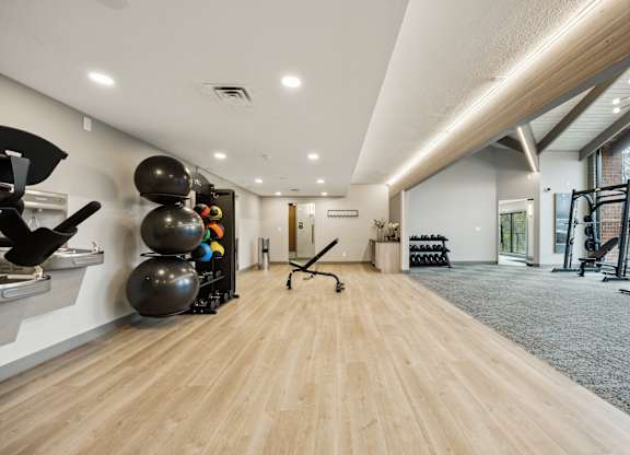 a workout room with weights and mirrors and a large window