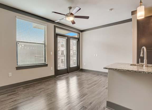 Pet-Friendly Apartments in Nashville, TN- Octave Apartments- Living Room with patio doors large windows wood style flooring and a ceiling fan