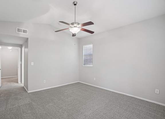 A room with a ceiling fan and carpeted floor.