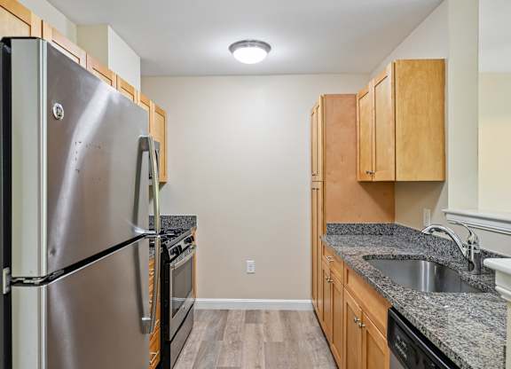 A kitchen with a stainless steel refrigerator and wooden cabinets.