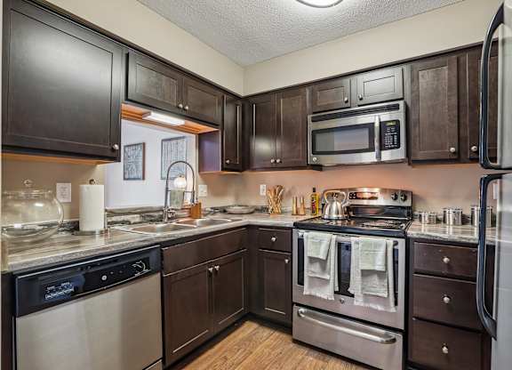 A kitchen with dark wood cabinets and stainless steel appliances.