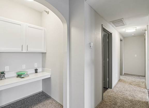 A hallway with a white cabinet and a grey carpet.