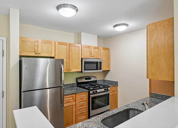 A kitchen with a stainless steel refrigerator, microwave, oven, and sink.