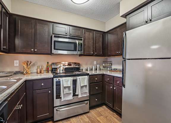 A kitchen with dark wood cabinets and stainless steel appliances.