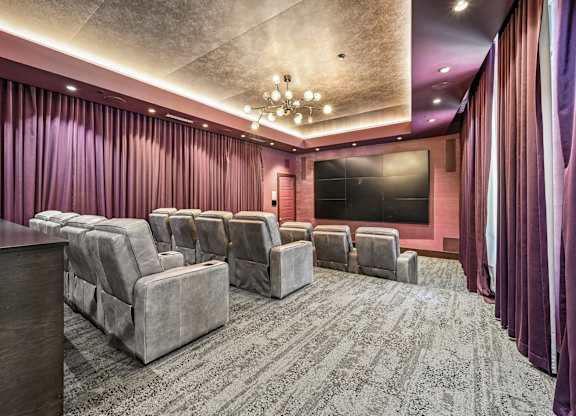 A room with a carpeted floor and a row of grey couches.