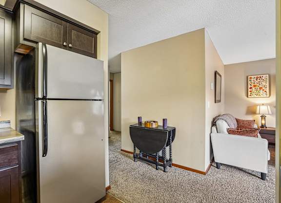 A kitchen with a refrigerator, a table with a black tablecloth, and a couch with pillows.