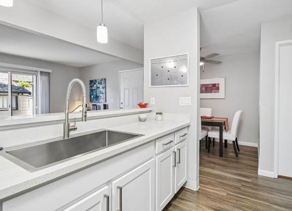 A kitchen with white cabinets and a stainless steel sink.