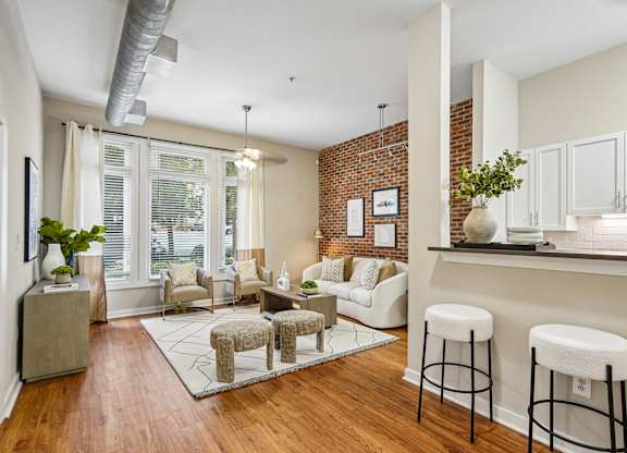A living room with a white couch and a brick wall.
