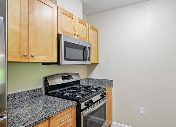A kitchen with a stove, microwave, and cabinets.