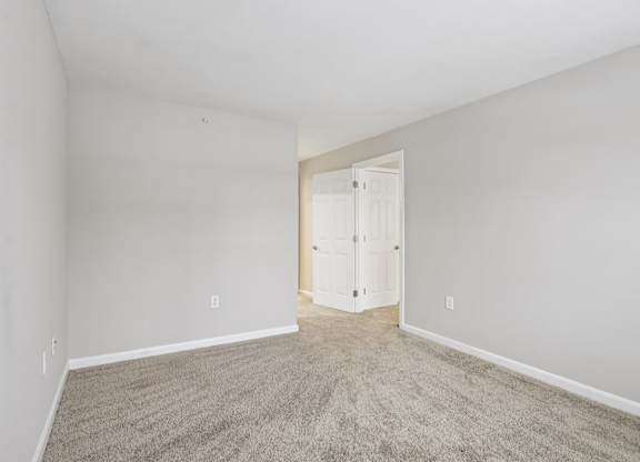 A room with a carpeted floor and a white door.