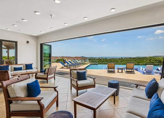 A modern living room with a view of the pool and outdoor furniture.