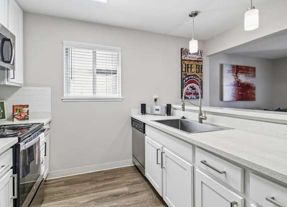 A kitchen with white cabinets and a wooden floor.