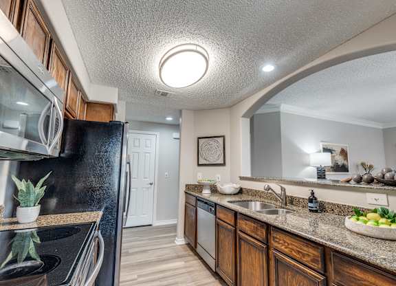 A kitchen with a black refrigerator and wooden cabinets.