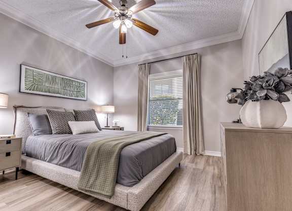 A bedroom with a bed, nightstand, and a ceiling fan.