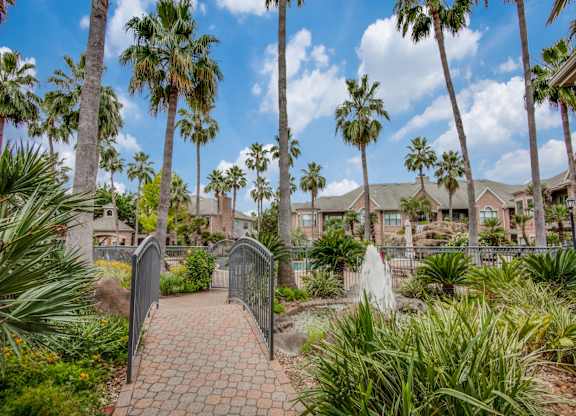 Apartments For Rent In West Houston - San Montego - Courtyard With Water Fountain, Palm Trees, Walk Way, And Maintained Landscaping
