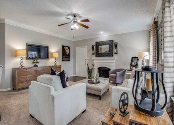 Two-Bedroom Apartments in West Houston TX - San Montego Apartments Spacious Living Room Area with Carpet Flooring, a Fire Place, Ceiling Fan, and Windows for Natural Light