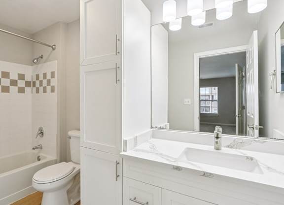 A white bathroom with a toilet, sink, and shower.