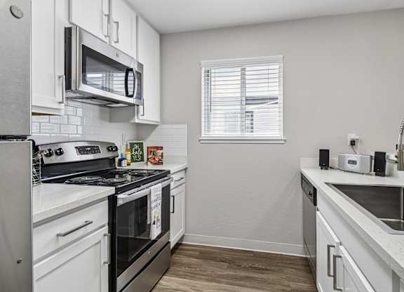 A kitchen with white cabinets and appliances.