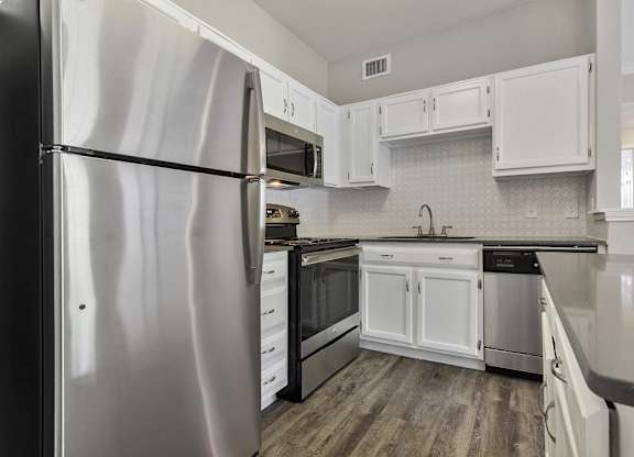 Apartments for Rent in Plano, TX - Carrington Park Kitchen with Stainless Steel Appliances, White Cabinets, and White Tile Backsplash