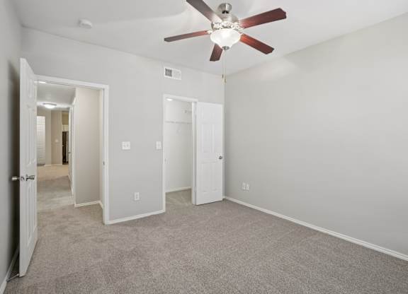 A room with a ceiling fan and carpeted floor.