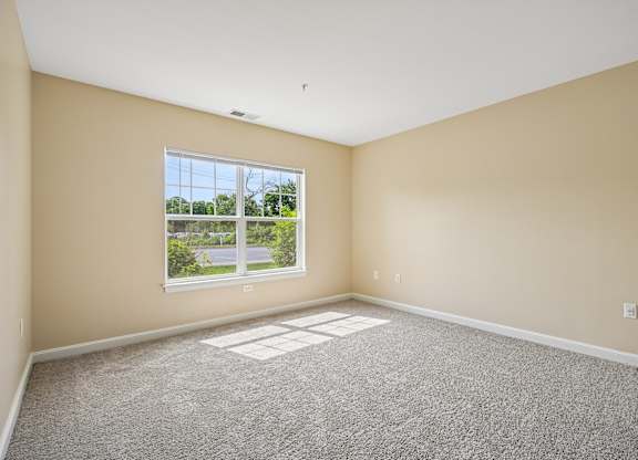 A room with a large window and carpeted floor.