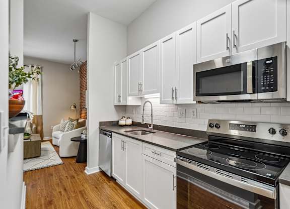 A kitchen with white cabinets and a black stove top oven.